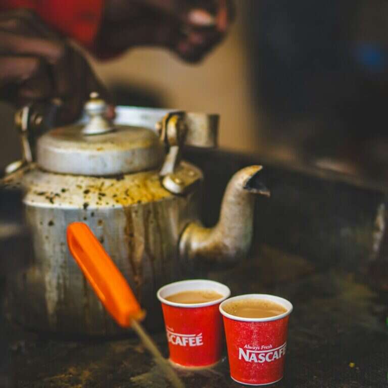 Cups of masala chai beside a kettle